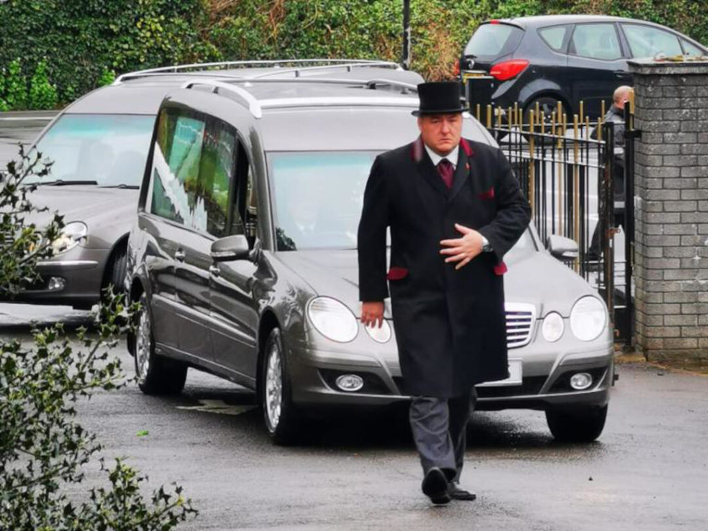 Funeral director walking in from of hearse